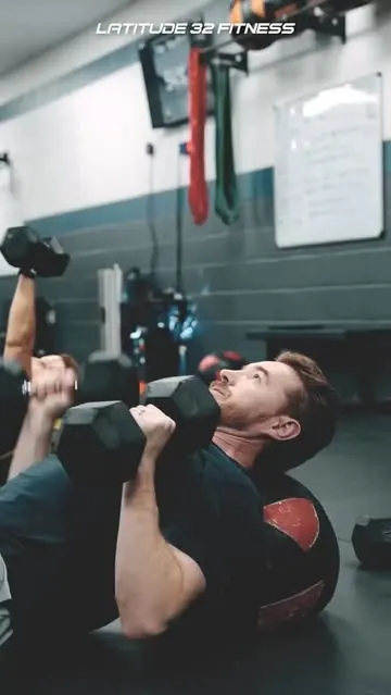 Member learning a dumbbell floor press at Latitude 32 Fitness